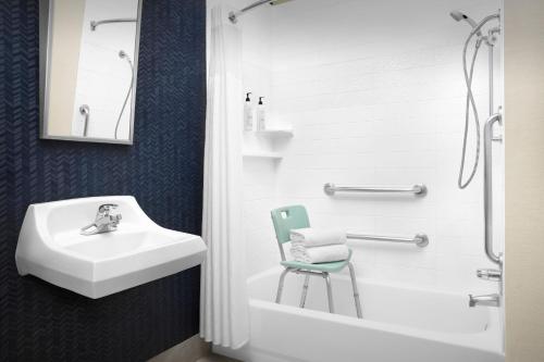 a bathroom with a sink and a chair next to a shower at Fairfield Inn & Suites Dulles Airport in Sterling