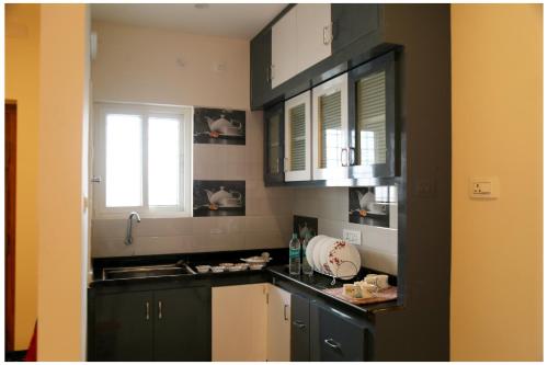 a kitchen with black and white cabinets and a sink at Padmavathi Homestay -2BHK 1BHK AC Apartments for group of families - Best location - Flyover to Alipiri gate - Walk to PS4 Veg Restaurant - Modular Kitchen - Super fast Wi-Fi- Near to Tirupati Bus Stand 2 KM-Near to Railway Station 2KM in Tirupati