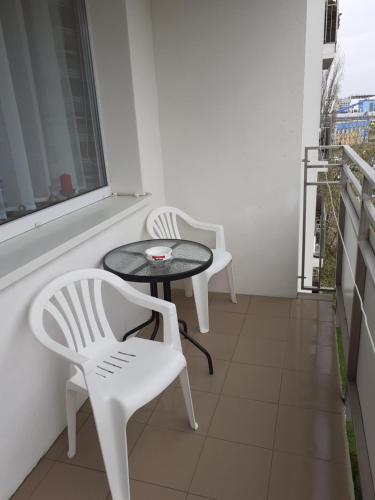 two white chairs and a table on a balcony at Apartament Szept Plaży in Kołobrzeg