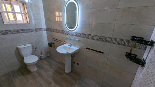 a bathroom with a toilet and a sink and a mirror at Clarisse lodge in Lomé