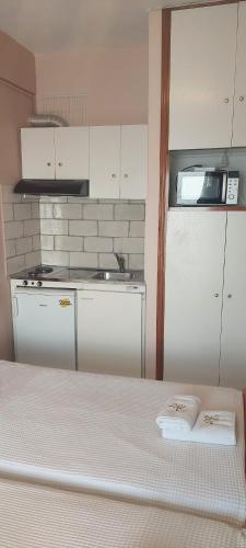 a kitchen with white cabinets and a bed in a room at Seaside Studios in Paralia Dionysiou