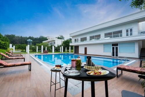 uma mesa com comida ao lado de uma piscina em Corbett The Regnum Resort em Rāmnagar