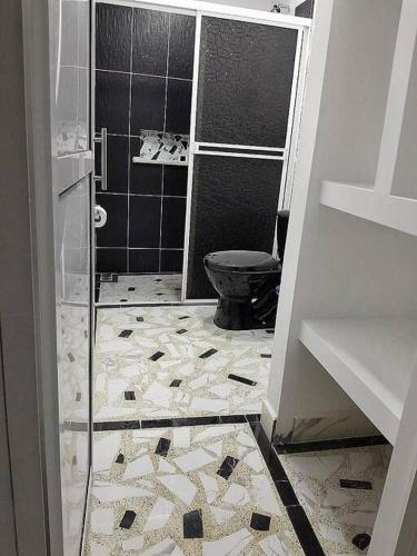 a bathroom with a black toilet and a tile floor at Parcela - Casa del árbol in Doradal