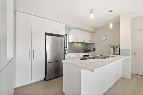 a kitchen with white cabinets and a stainless steel refrigerator at Villa Dante - walk to town - brand new town house in Margaret River Town