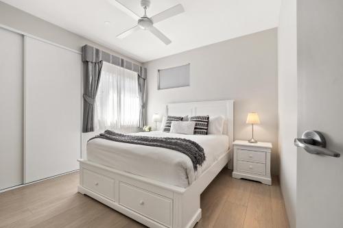 a white bedroom with a white bed and a window at Villa Dante - walk to town - brand new town house in Margaret River Town