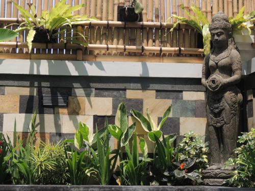 a statue of a woman on a wall with plants at Natha Ubud Villa in Ubud