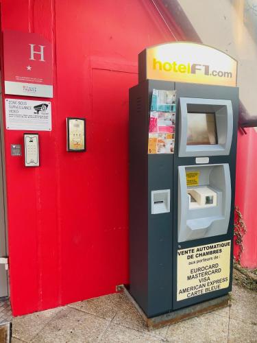 a parking meter in front of a red wall at HôtelF1 Angoulême in Champniers