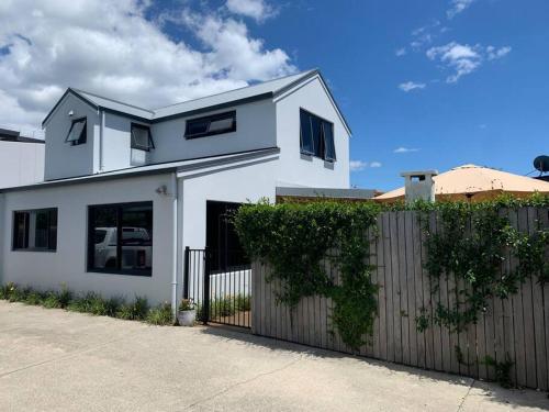 a white house with a fence in front of it at Cosy on Campbell in Mount Maunganui