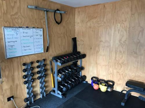 a room with a bunch of dumbbells on a wall at Cosy on Campbell in Mount Maunganui