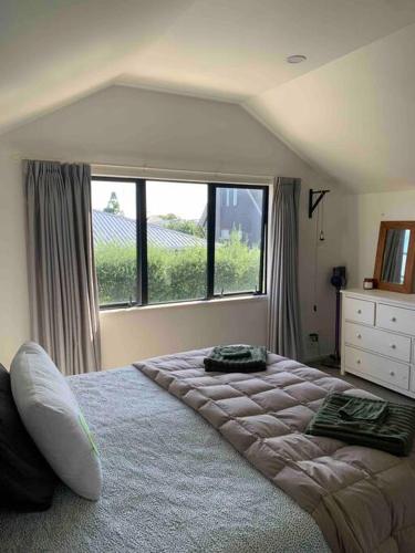 a bedroom with a large bed with a large window at Cosy on Campbell in Mount Maunganui