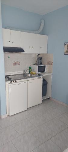 a kitchen with white cabinets and a sink at Seaside Studios in Paralia Dionysiou