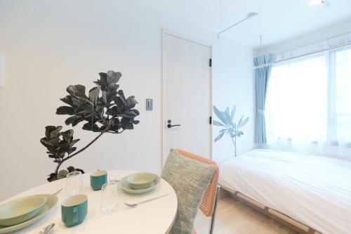 a white bedroom with a table and a bed at RIZOTIA Hakusan by Tranova in Tokyo