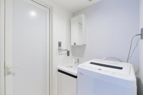 a white kitchen with a sink and a washing machine at RIZOTIA Hakusan by Tranova in Tokyo