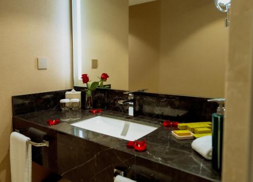 a bathroom with a sink and a mirror and red roses at Hilton Al Khobar King Fahd Causeway in Al Khobar