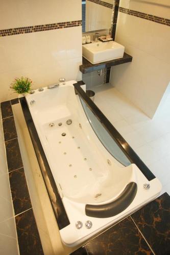 a bathroom with a bath tub and a sink at Grand Pink Hotel Hatyai in Hat Yai