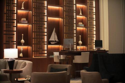 a lobby with chairs and a desk with a sailboat on the wall at Hilton Al Khobar King Fahd Causeway in Al Khobar
