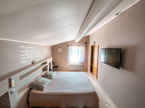 une chambre avec un lit et une télévision au mur dans l'établissement La Petite Colline, à Apt