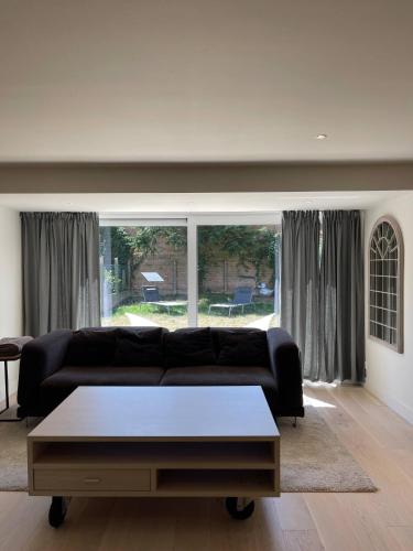 a living room with a black couch and a coffee table at Modern Flat With Garden in Ostend