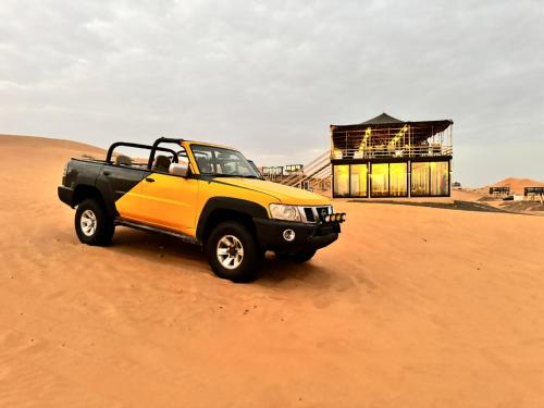 a yellow and black truck parked in the desert at Oman desert private camp in Shāhiq
