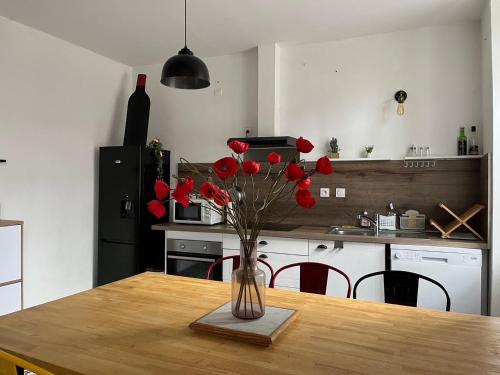 eine Vase roter Blumen auf einem Tisch in der Küche in der Unterkunft La maison du pont vieux - emplacement de parking gratuit - Proche Cité médiévale in Carcassonne
