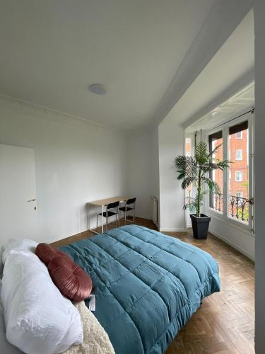 une chambre avec un grand lit bleu et une fenêtre dans l'établissement Creativity Quarters Habitación temporada en coliving para estudiantes, trabajadores y artistas, à Madrid