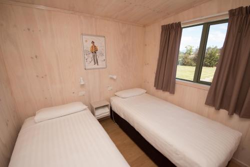 two beds in a small room with a window at Martinborough TOP 10 Holiday Park in Martinborough 