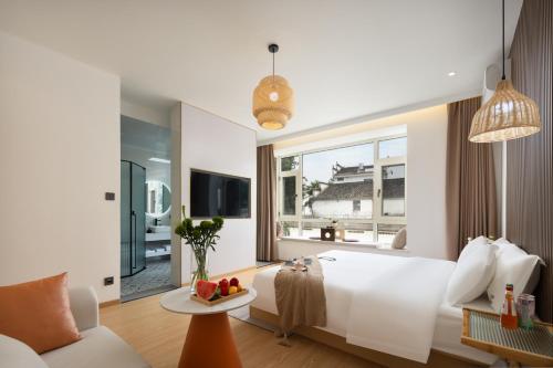 a bedroom with a large white bed and a living room at 婺源县那湾那月民宿婺女洲店 in Xikeng