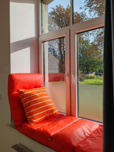 a red couch sitting in front of a window at homecoming in Rīga
