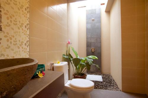 bagno con servizi igienici, lavandino e pianta di Saka Village Resort Ubud ad Ubud