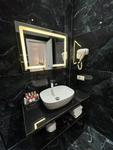 a black bathroom with a sink and a mirror at Hotel Panorama & Spa Elbasan in Elbasan