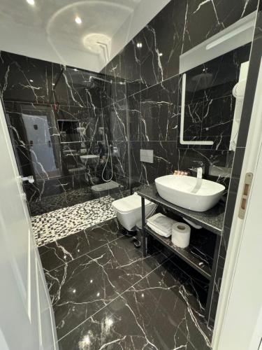a black marble bathroom with a sink and a mirror at Hotel Panorama & Spa Elbasan in Elbasan