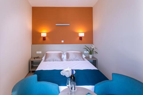 a bedroom with a bed and two blue chairs at Apartments Villa Loznica in Brela