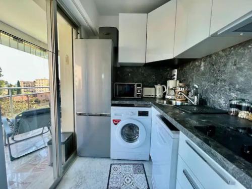 une cuisine avec un lave-linge et un réfrigérateur dans l'établissement Grande terrasse vue dégagée mer en Basse Californie, à Cannes