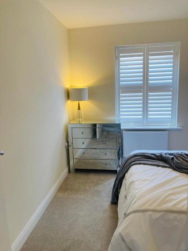a bedroom with a bed and a dresser with a lamp at House-Sleeps 8-Parking-Garden in Weekley