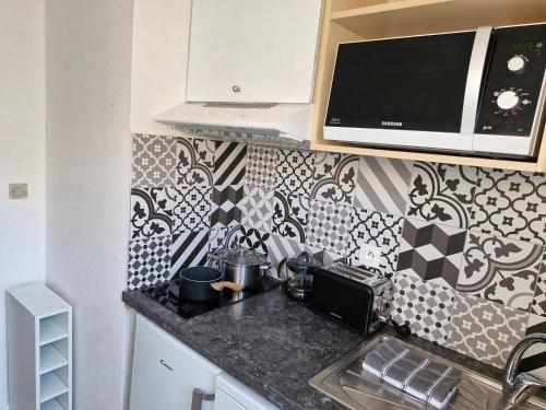 a kitchen with black and white tiles on the wall at KSL Vos vacances dans les Landes in Soustons