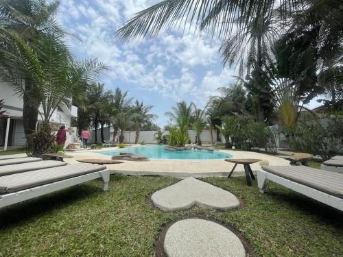 a swimming pool with two benches in a yard at Oasis club in Cap Skirring
