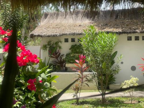 a garden with flowers and a building with a thatch roof at Oasis club in Cap Skirring