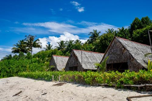 two buildings on the beach with trees in the background at Ira Bungalows Pulau Banyak in Alaban