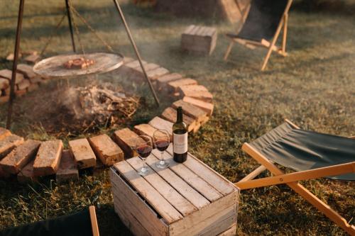 two glasses of wine on a wooden table next to a fire at Śliwkowy Sad-Plum Orchard-Jura in Mirów