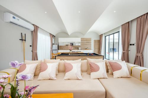 a living room with a white couch with pink and white pillows at come home pool villa cha-am in Phetchaburi