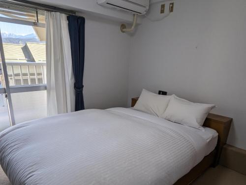 a bed with white sheets and a window with a view at Hotel WWJ in Ina