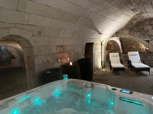 a bath tub in a stone room with chairs at Gîte Au Boom Coeur - petit déjeuner inclus - SPA en option in Tourtenay