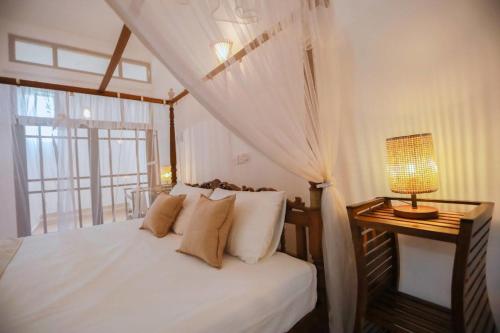 a bedroom with a bed and a table with a lamp at Nibbana Mirissa Hotel in Mirissa