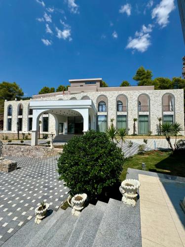 a large white building with a tree in front of it at Hotel Panorama & Spa Elbasan in Elbasan