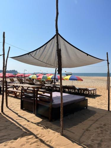 a canopy bed on the beach with umbrellas at Drishti yoga international in Patnem