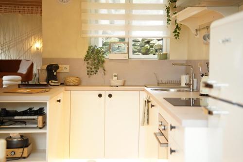 une cuisine avec des armoires blanches, un évier et une fenêtre dans l'établissement Maison atypique Alsace - Là Haut, à Lautenbach