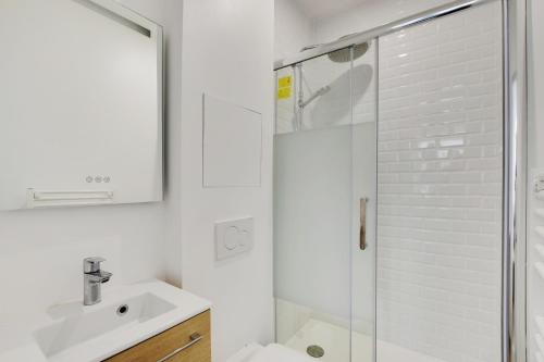 une salle de bain blanche avec une douche et un lavabo dans l'établissement Studio lumineux au centre de Vincennes, à Vincennes