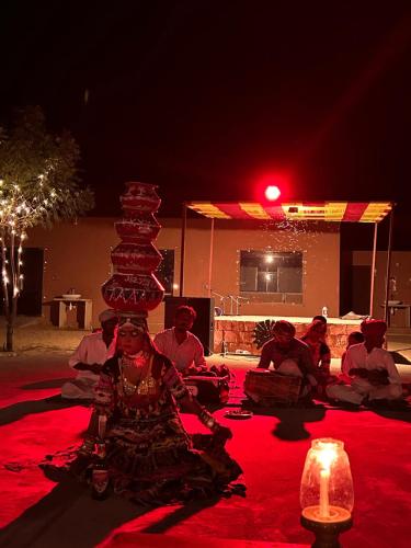 a group of people sitting on a red carpet with a stack of cakes at Sunny Desert Camp in Kūri