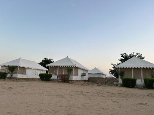 a row of white tents with white roofs at Sunny Desert Camp in Kūri