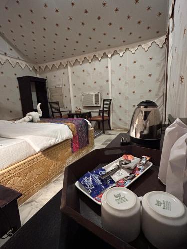 a bedroom with a bed and a table with a tray of food at Sunny Desert Camp in Kūri